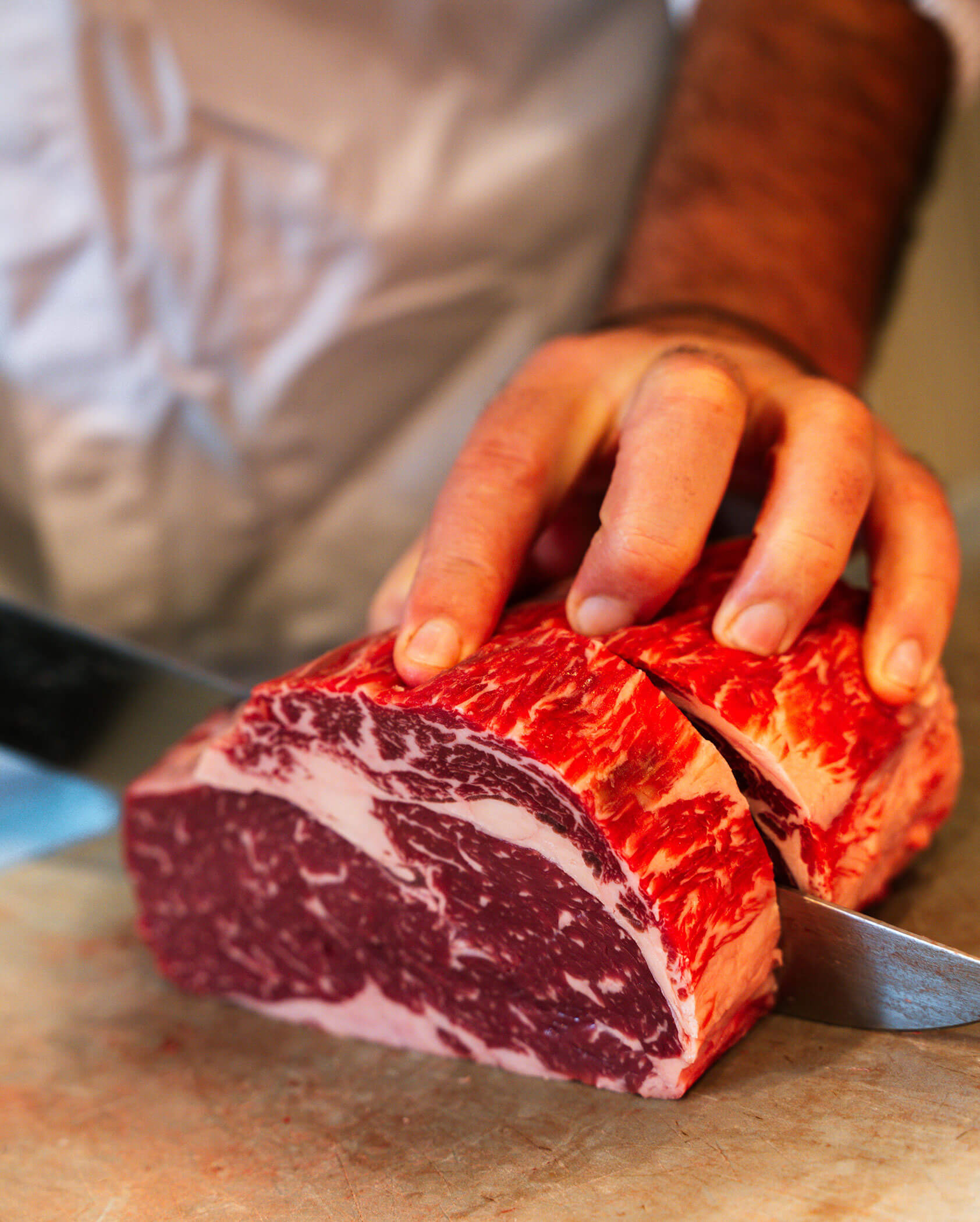 Metzger schneidet ein Stück Fleisch auseinander - Metzgerei Senfter