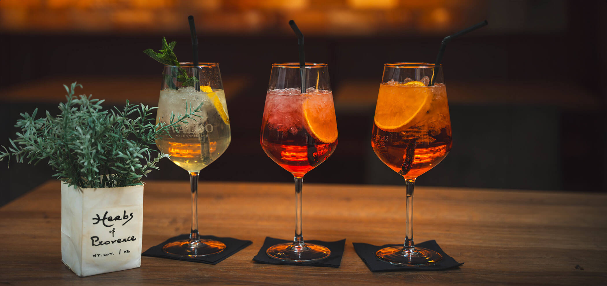 Drei Aperitifgetränke auf einem Holztisch im Senfter's Bistro - Metzgerei Senfter
