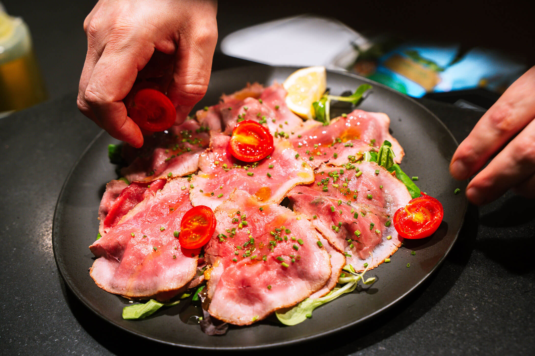 Koch vom Senfter's Bistro verfeinert das Fleisch mit frischen Tomaten - Metzgerei Senfter