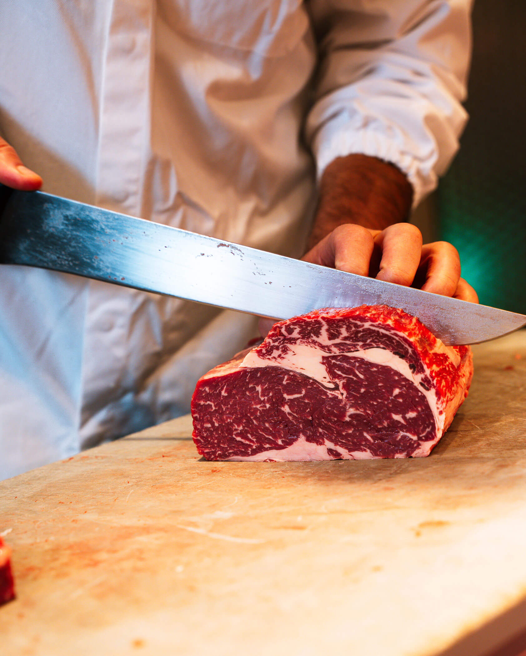 Metzger schneidet ein Stück Fleisch auseinander - Metzgerei Senfter